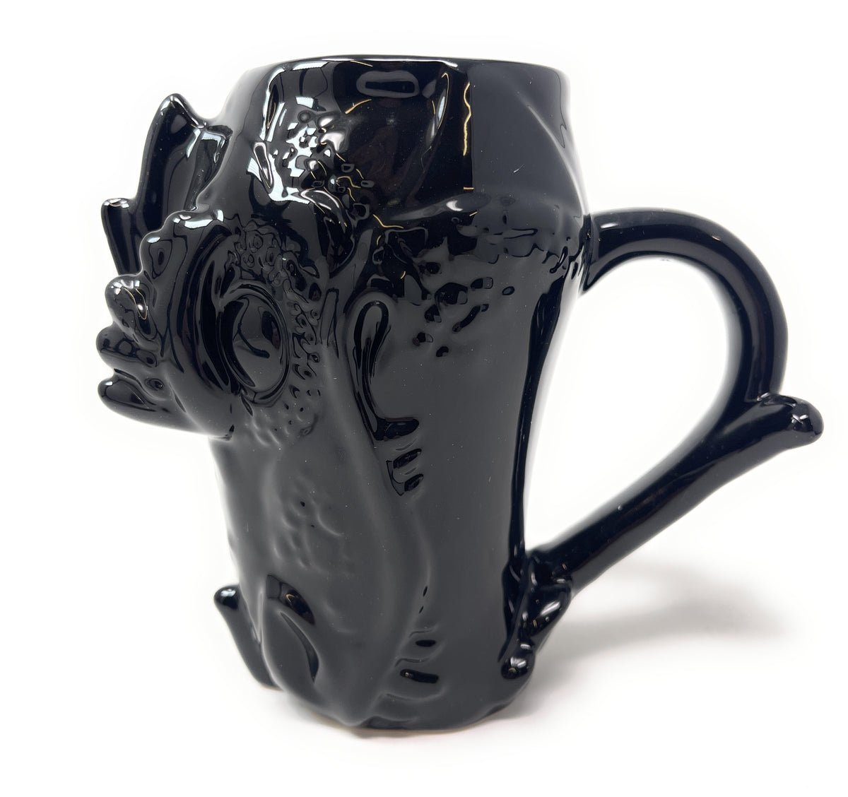 A glossy black ceramic mug shaped like a stylized animal face with a curved handle, photographed on a plain white background.
