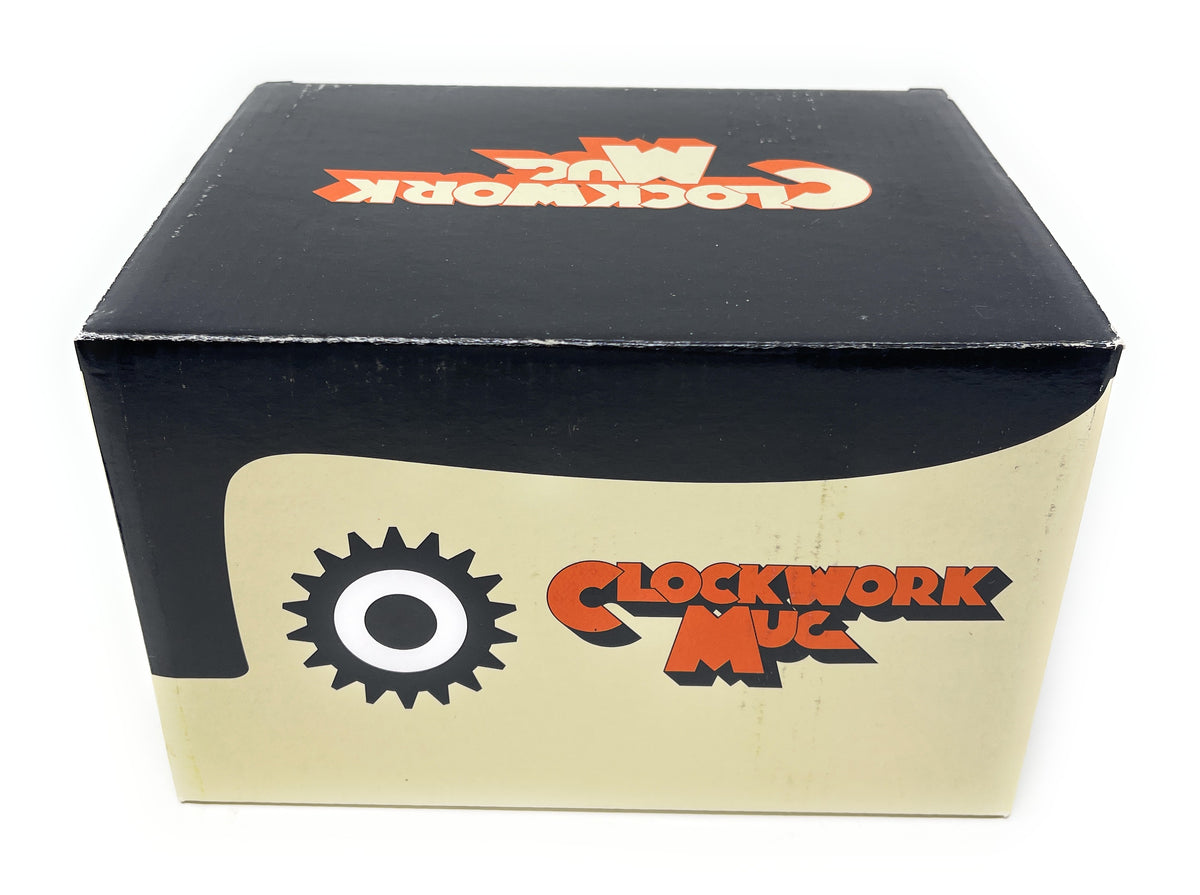 A square cardboard box for 'Clockwork Mug' featuring a black top half with an orange and white logo, and a cream-colored bottom half with a black gear logo and orange text.