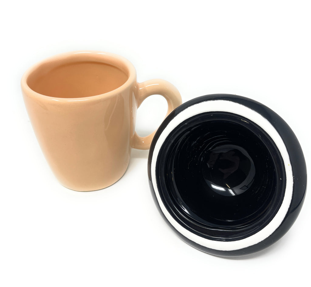 A beige Clockwork Orange Ceramic Mug shown next to its matching black and white lid on a plain white background.