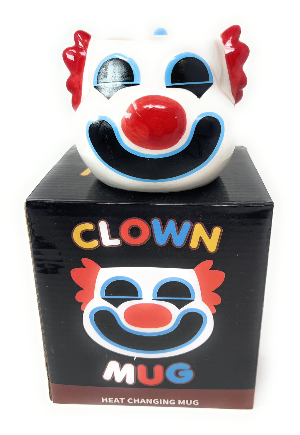A novelty heat changing clown mug sitting on top of its black retail box. The clown mug features a white face with a large red nose, red hair, and a black and blue smile.